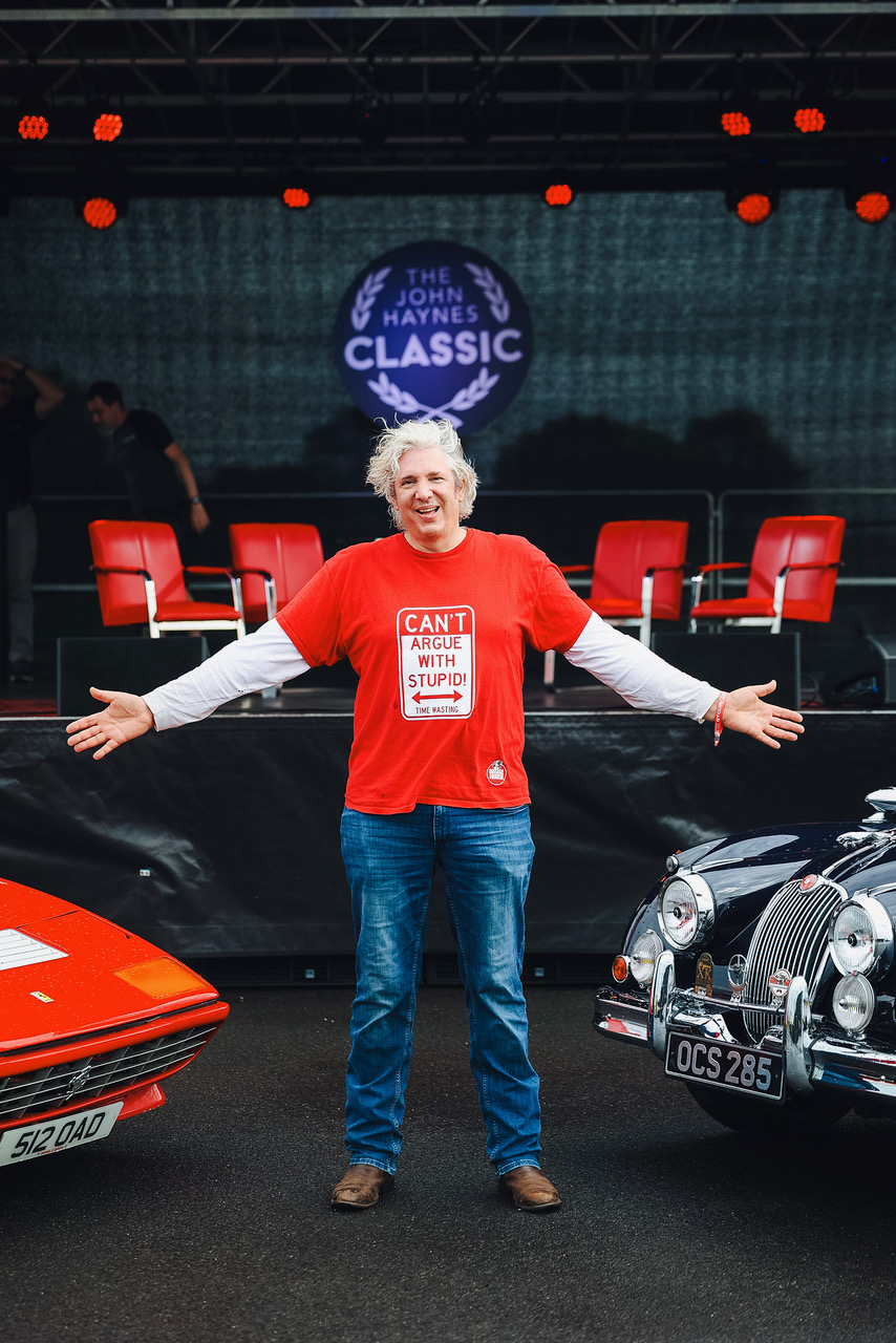 Edd China flanked by a Ferrari and a classic Jaguar XK150.