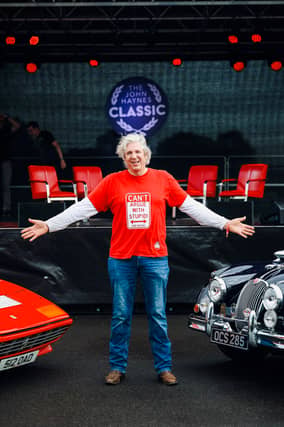 Edd China flanked by a Ferrari and a classic Jaguar XK150.