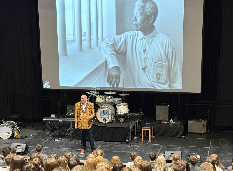 Chris Lubbe on stage at Torquay Academy with Nelson Mandela on  film in the background