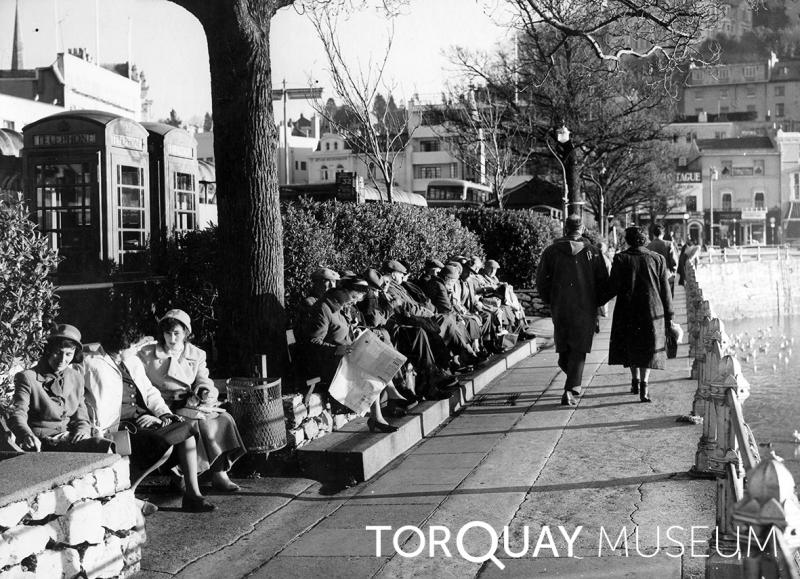 Residents enjoying the warm spring sunshine on the path between the inner harbour and Strand in 1960. #DigitalArchives