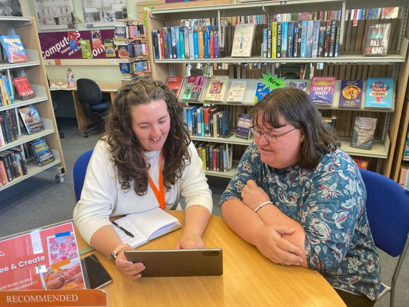 Individual receiving advice on how to use an iPad in a Devon library setting.