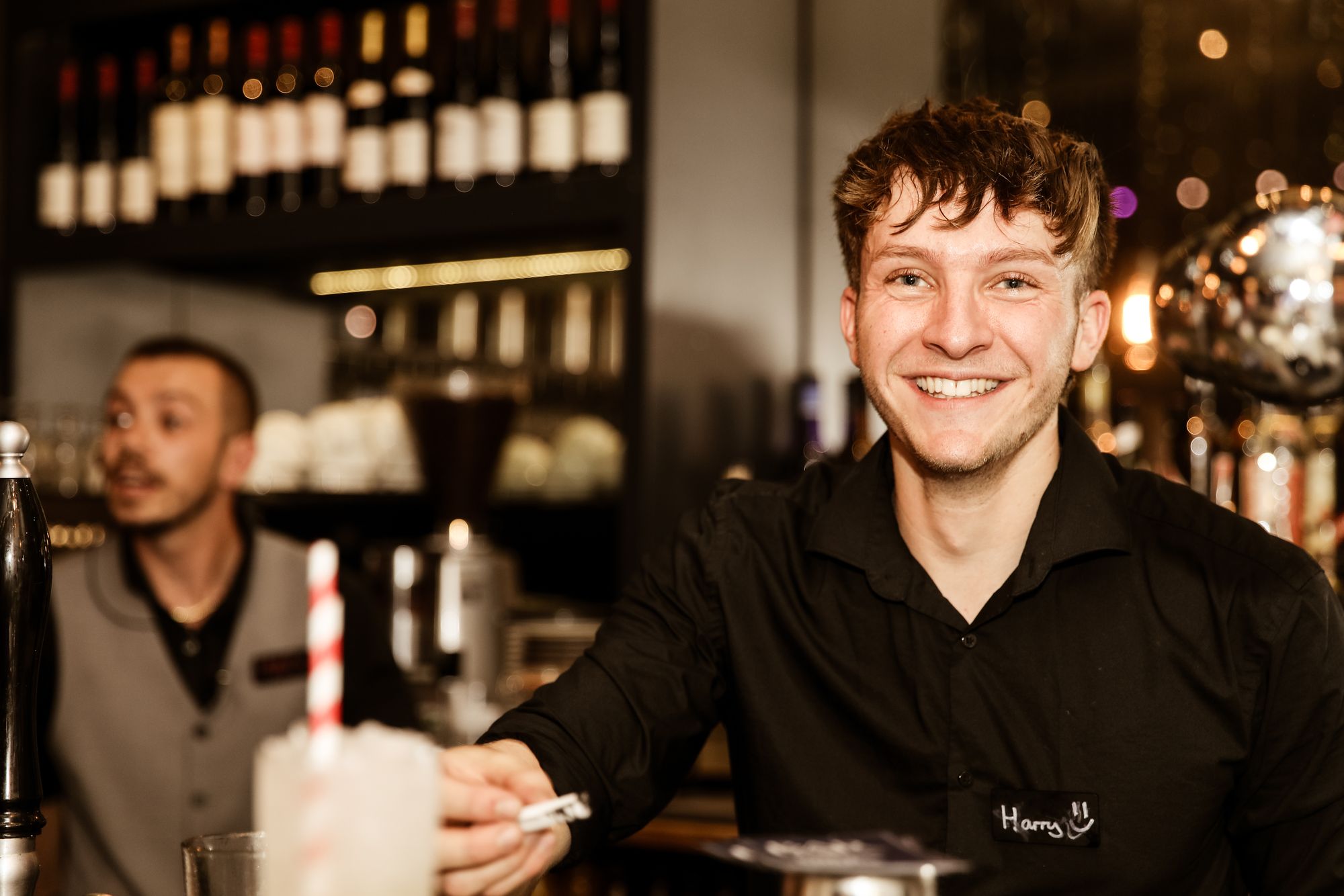 barman in black shirt grinning at camera