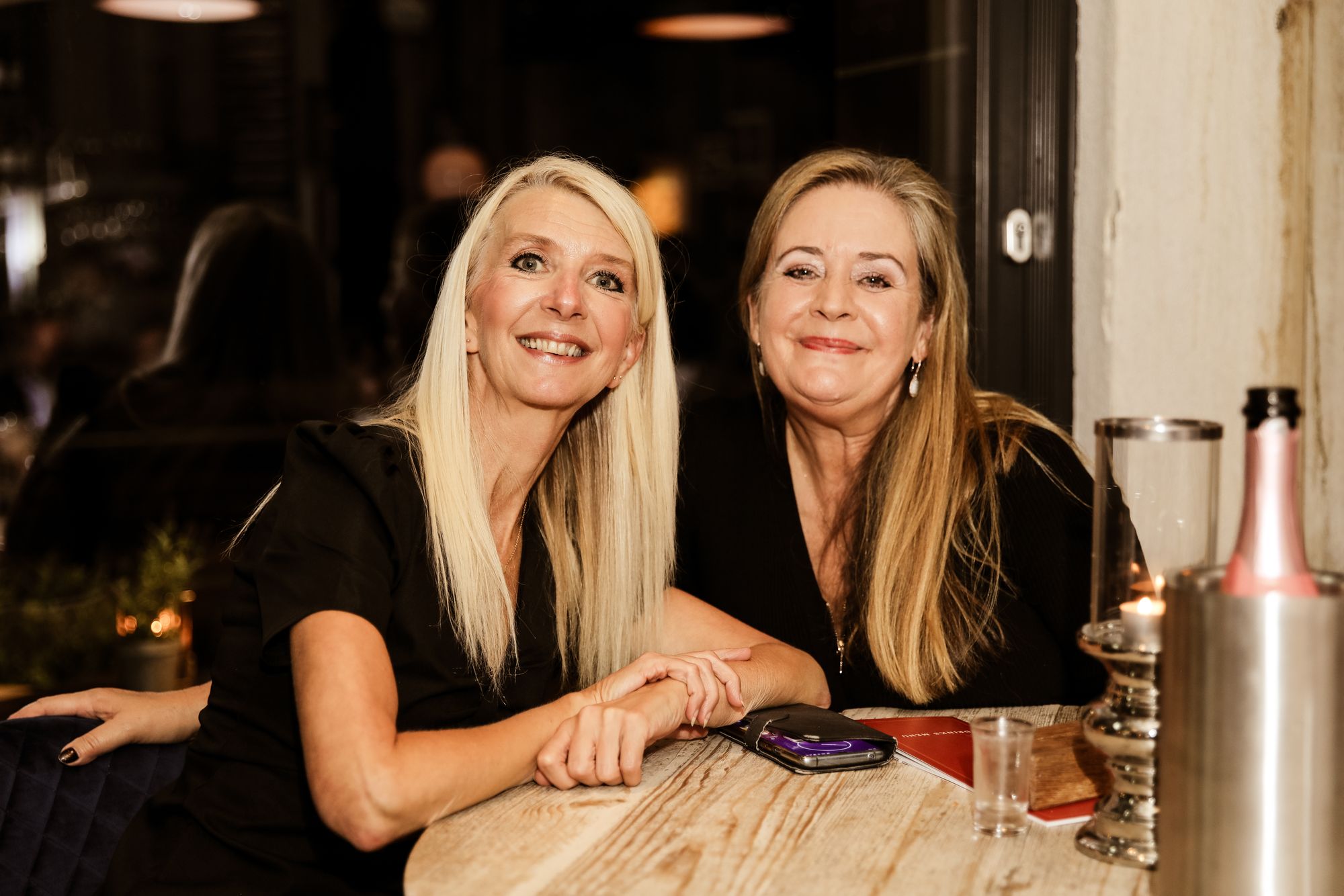 two women, both wearing black clothes, smiling at the camera