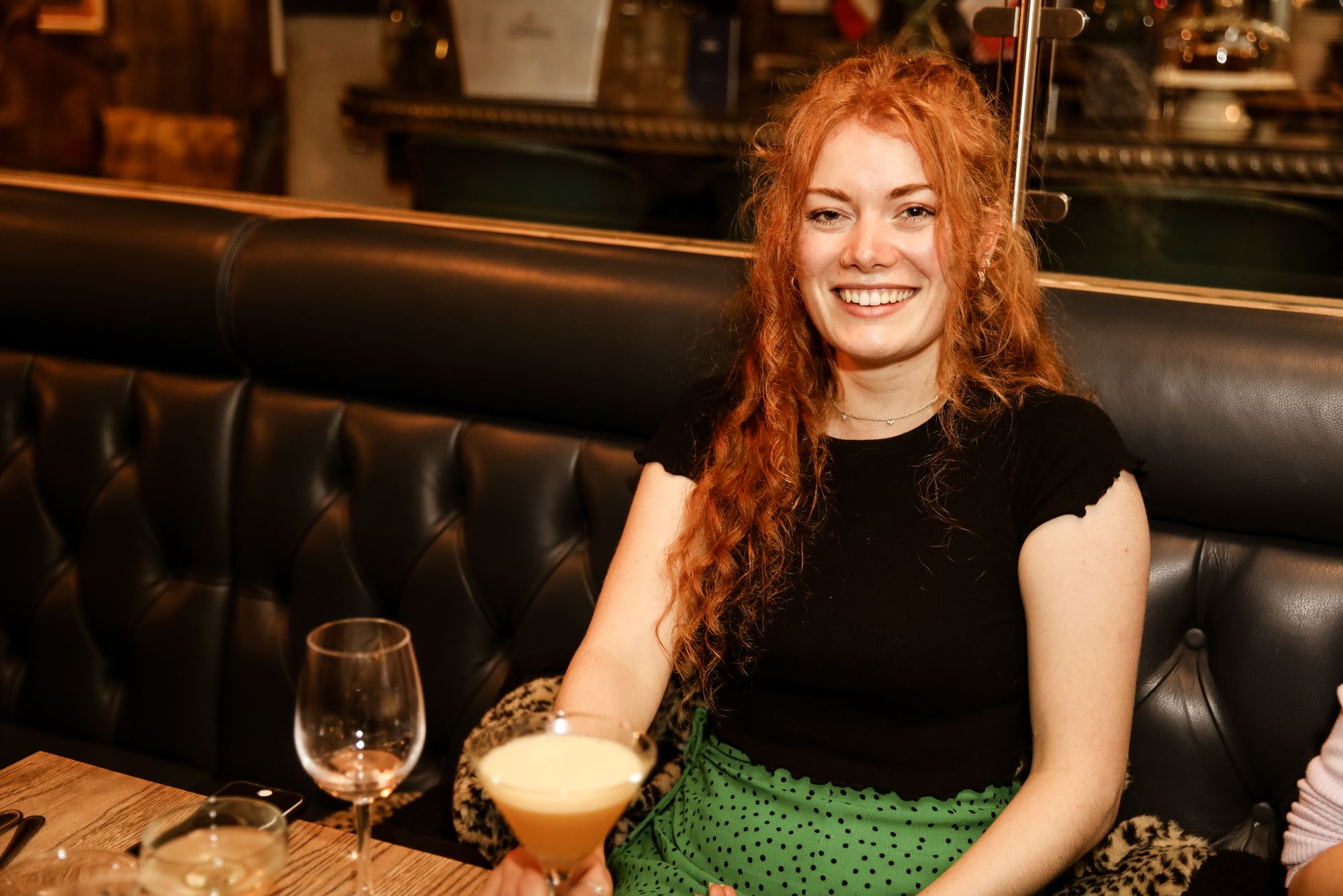 young auburn-haired woman sat with her cocktail