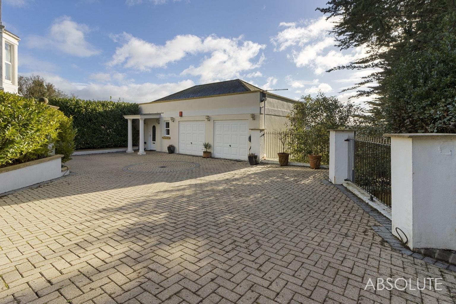 The property is accessed by electric gates leading to a driveway suitable for several cars and a double garage. Credit Absolute